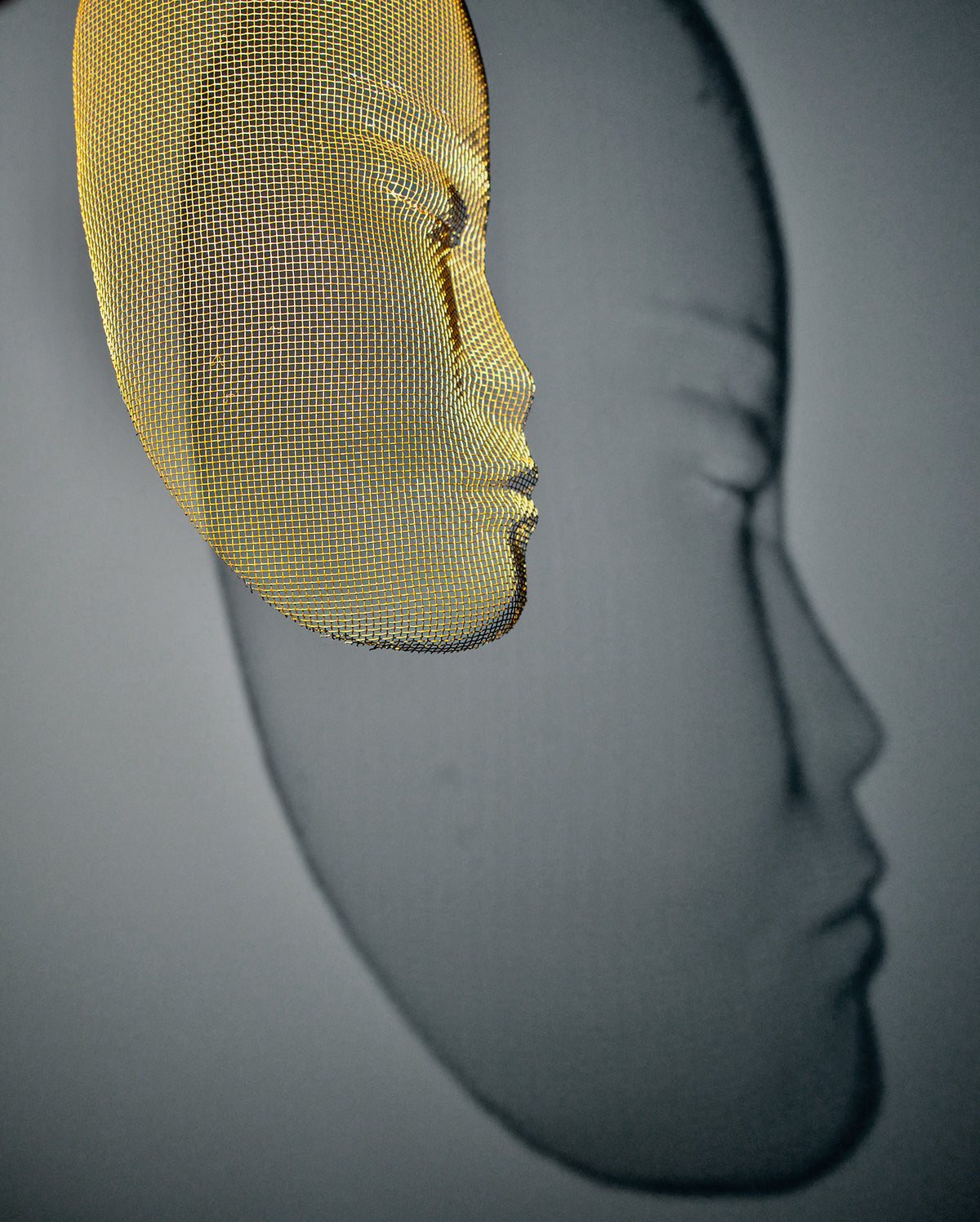 Side view of Arturo Álvarez illuminated mesh mask wall sculpture – handcrafted metallic mesh revealing sculptural depth, translucent texture and light